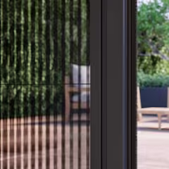 Zwart horrengaas in deuropening met wazig terras met tuinmeubels op de achtergrond