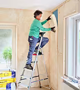 man brengt isolatie aan op wand
