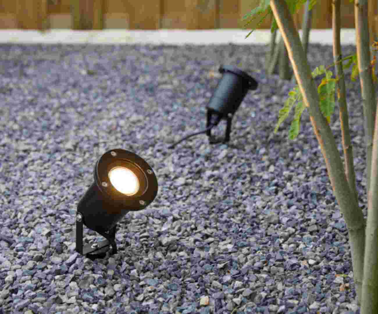 Twee zwarte tuinspots op grind die elk een plant verlichten