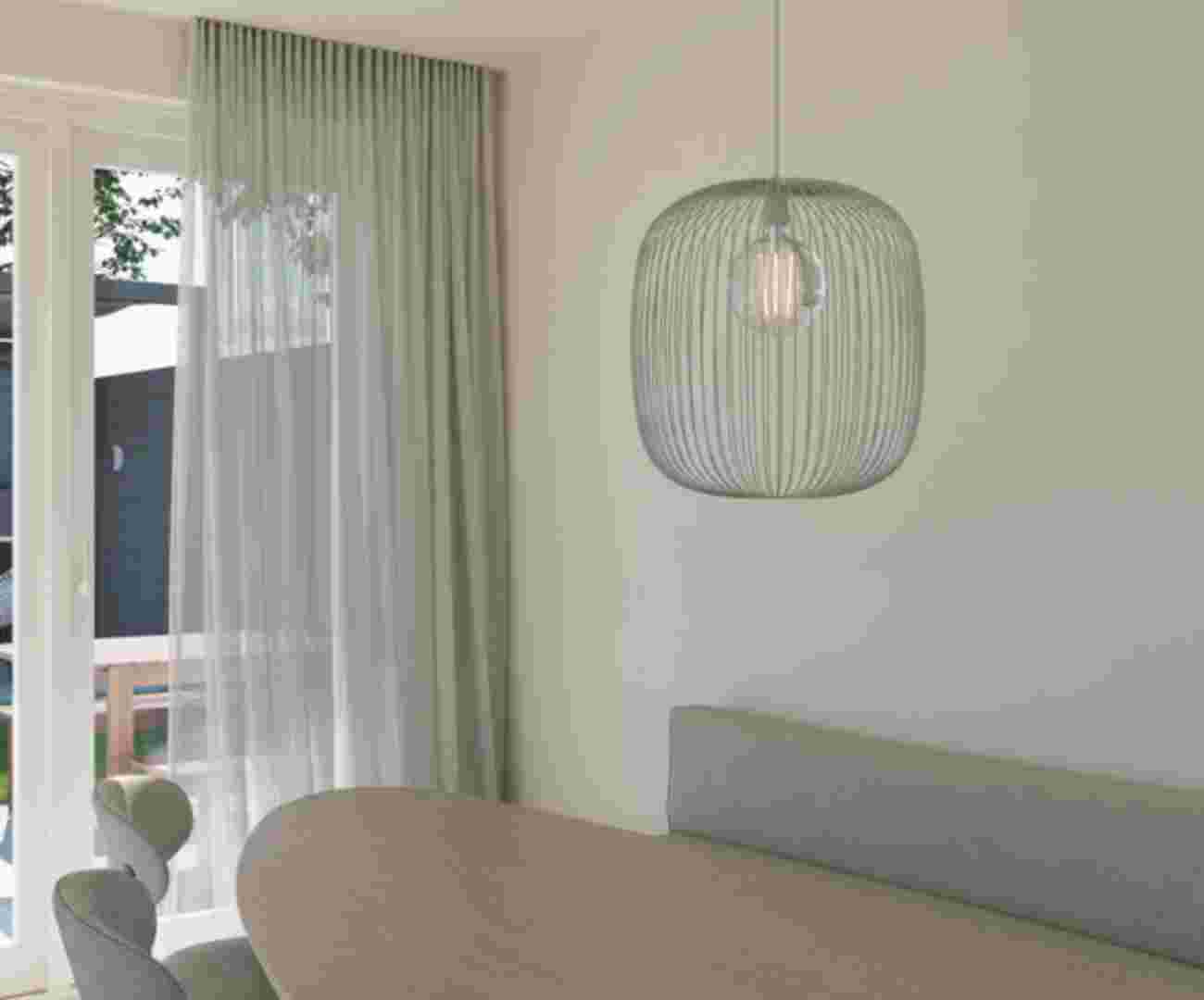 Moderne woonkamer met een ovale houtentafel en daarboven een grote hanglamp.