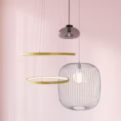 Moderne hangende lampen met twee ronde gouden schijven en een draadkooi-vormige glazen lamp tegen een witte muur.