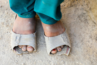 Shahnaz, (9) from Afghanistan shows her sandal to the camera.