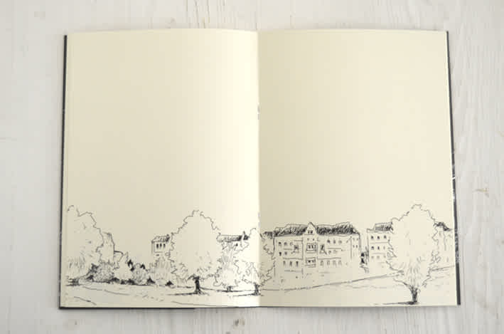 Image of an open notebook with drawings of houses and trees. 