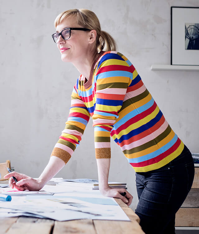 Woman wearing a colorful sweater looking out the window