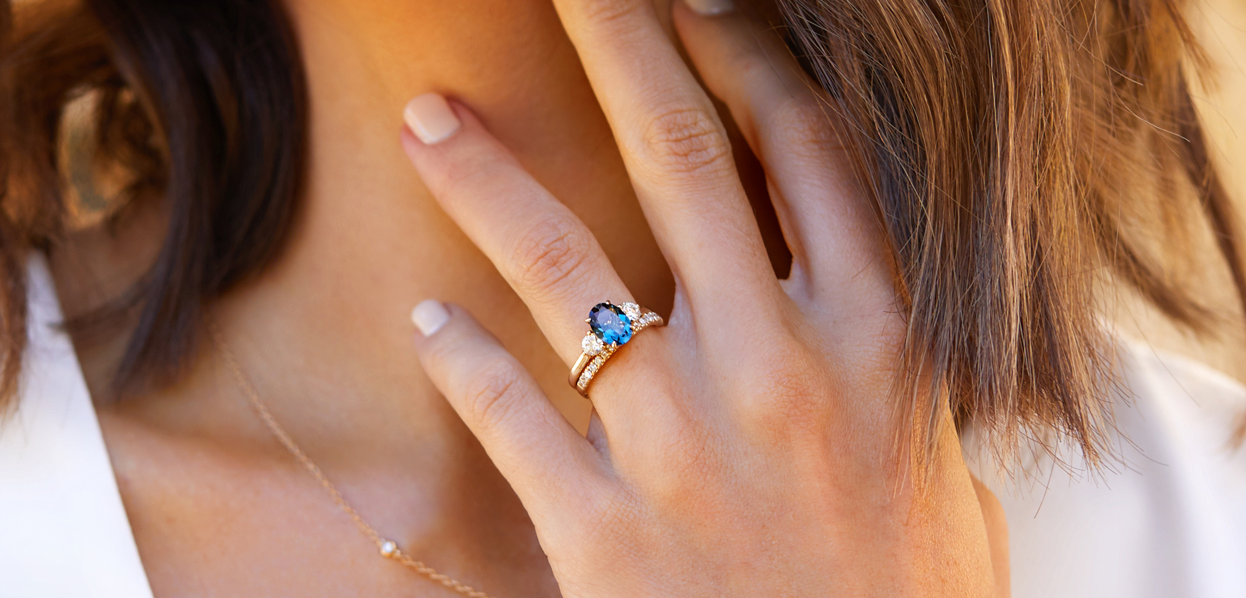 Close up of female hand wearing a blue topaz bridal set.