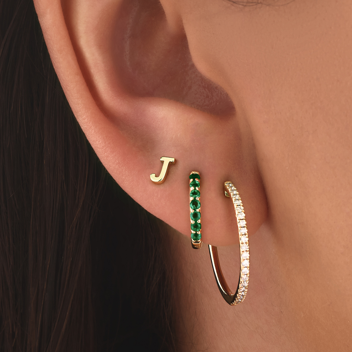 Diamond and emerald hoops stacked together with a J initial stud