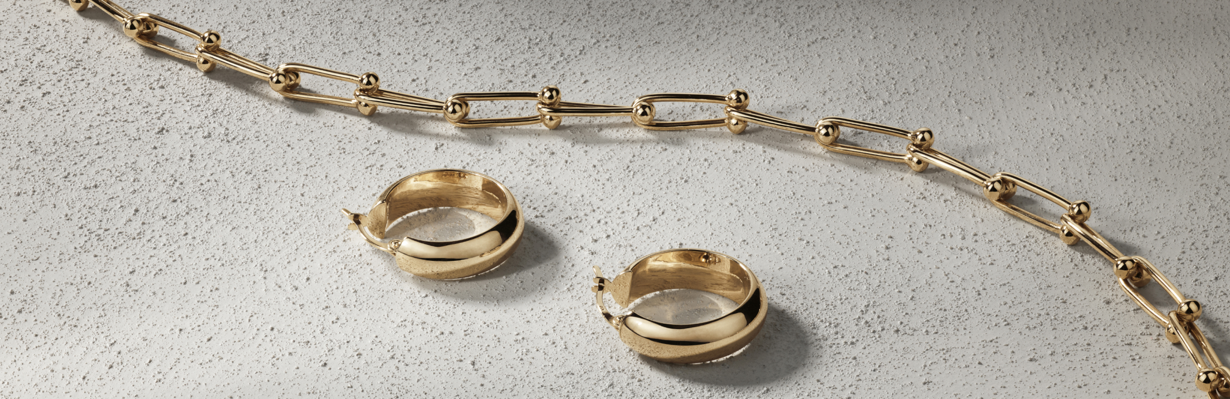 Flatlay of gold hoops and chain