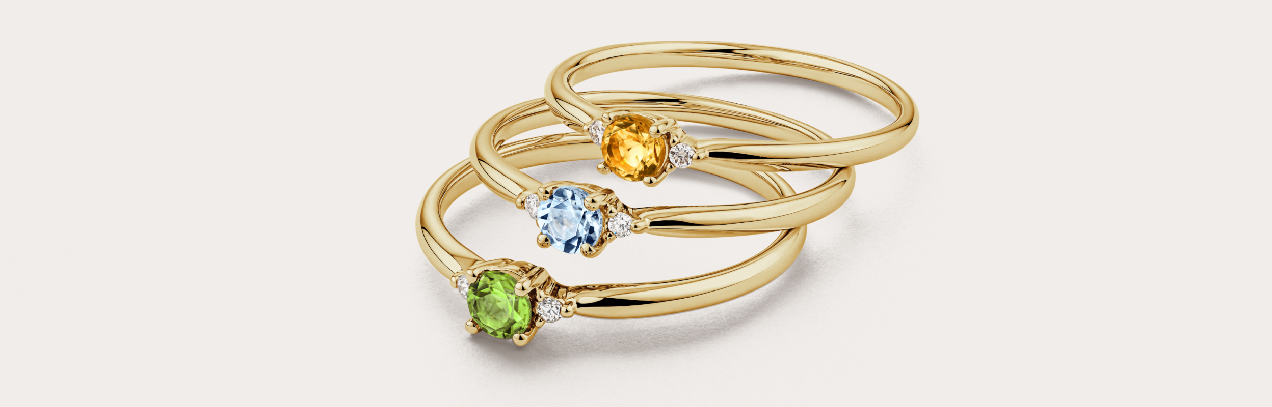three gold birthstone rings stacked