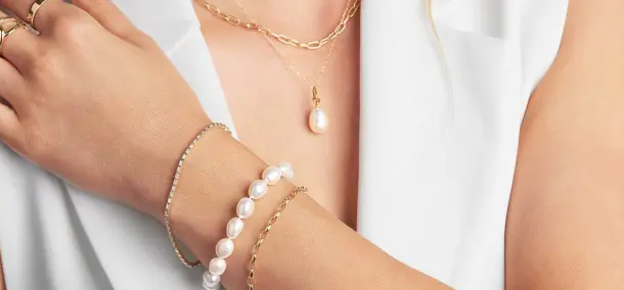 Femme portant un collier, des bagues et des bracelets en perles avec un collier, des bagues et des bracelets en or