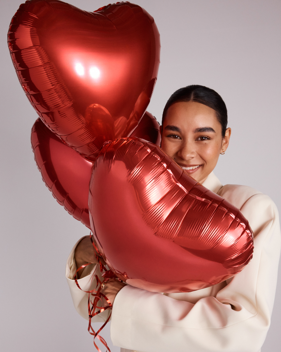 Model holding 3 red heart balloons 