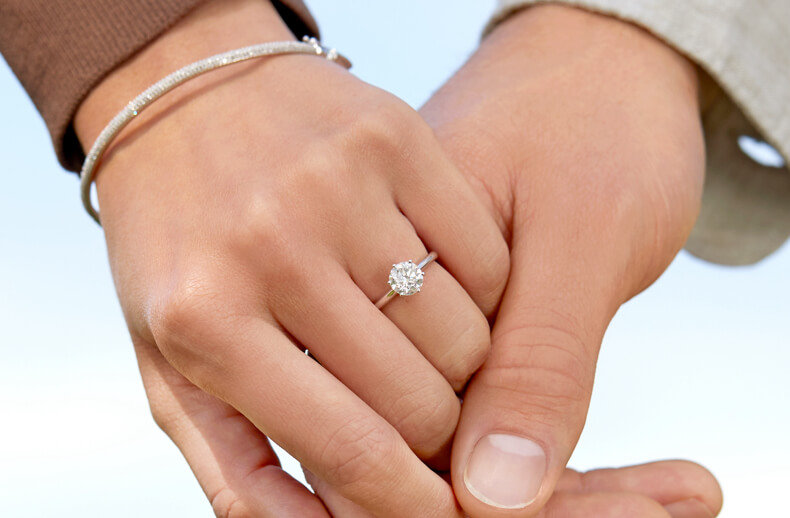 Hands being held with solitaire engagement ring and diamond bangle