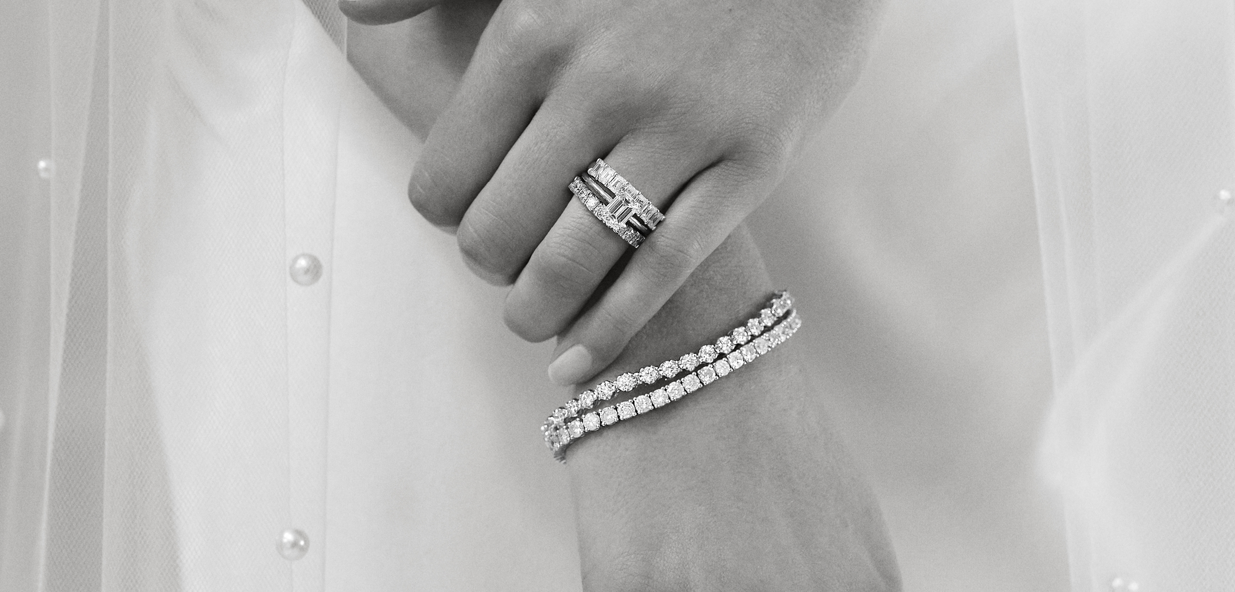 Main manucurée portant une bague de fiançailles avec des anneaux en diamant à la main gauche et des anneaux en or jaune à l'index 