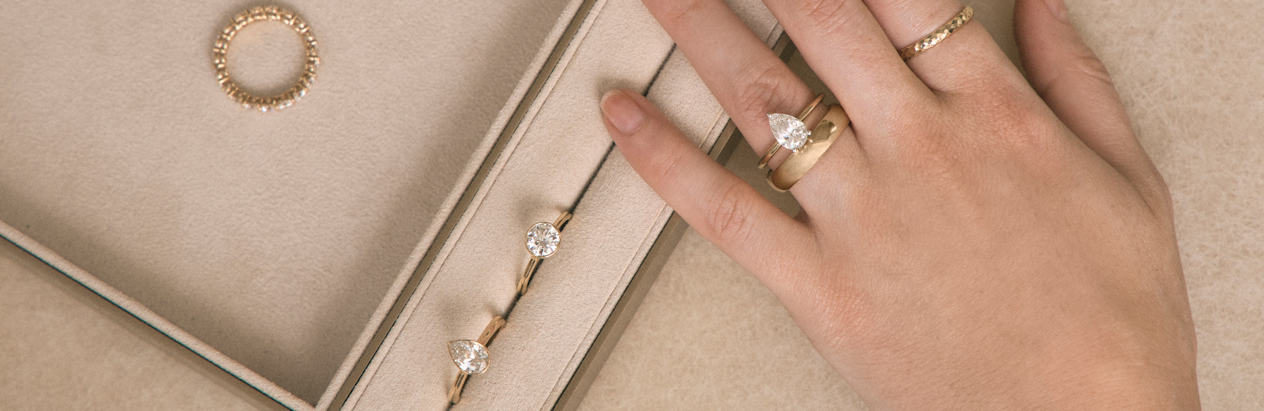 Close up of different engagement rings alongside a model's hand wearing an engagement ring and wedding band 