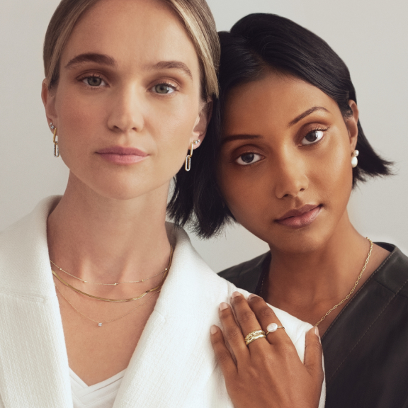 two girls wearing gold necklaces, earrings and rings