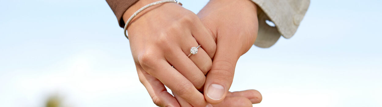 Couple holding hands with diamond bangle and engagement ring