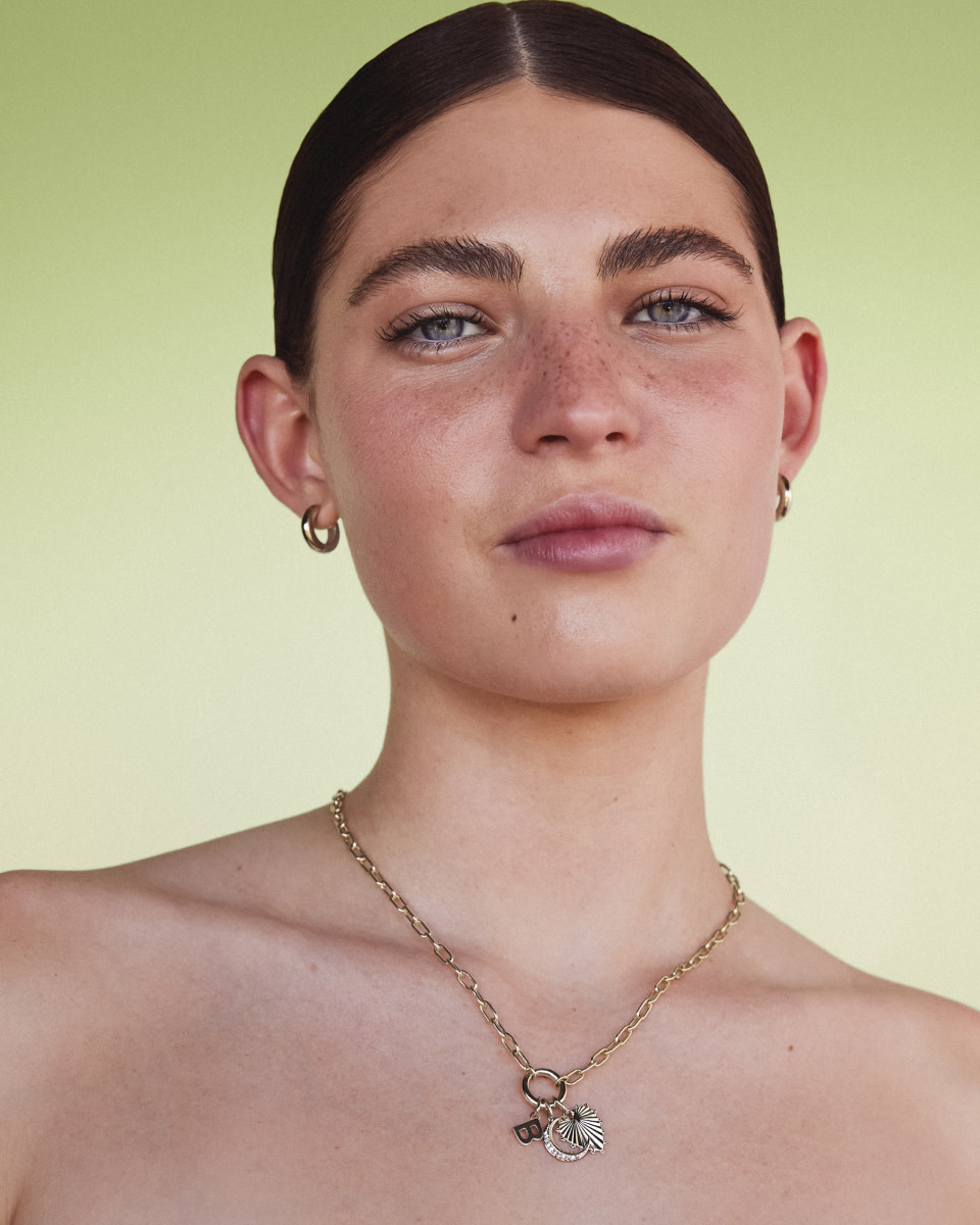 Close up of model wearing an open chain necklace and connector with mixed pendants 