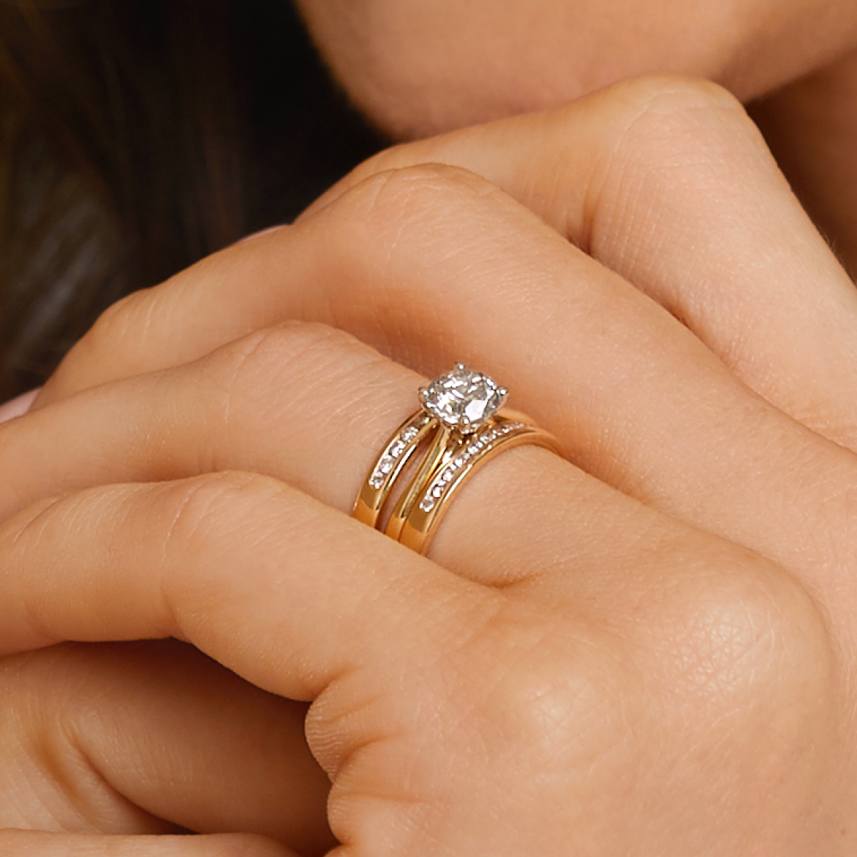 woman smiling whilst wearing engagement ring with diamond enhancer ring