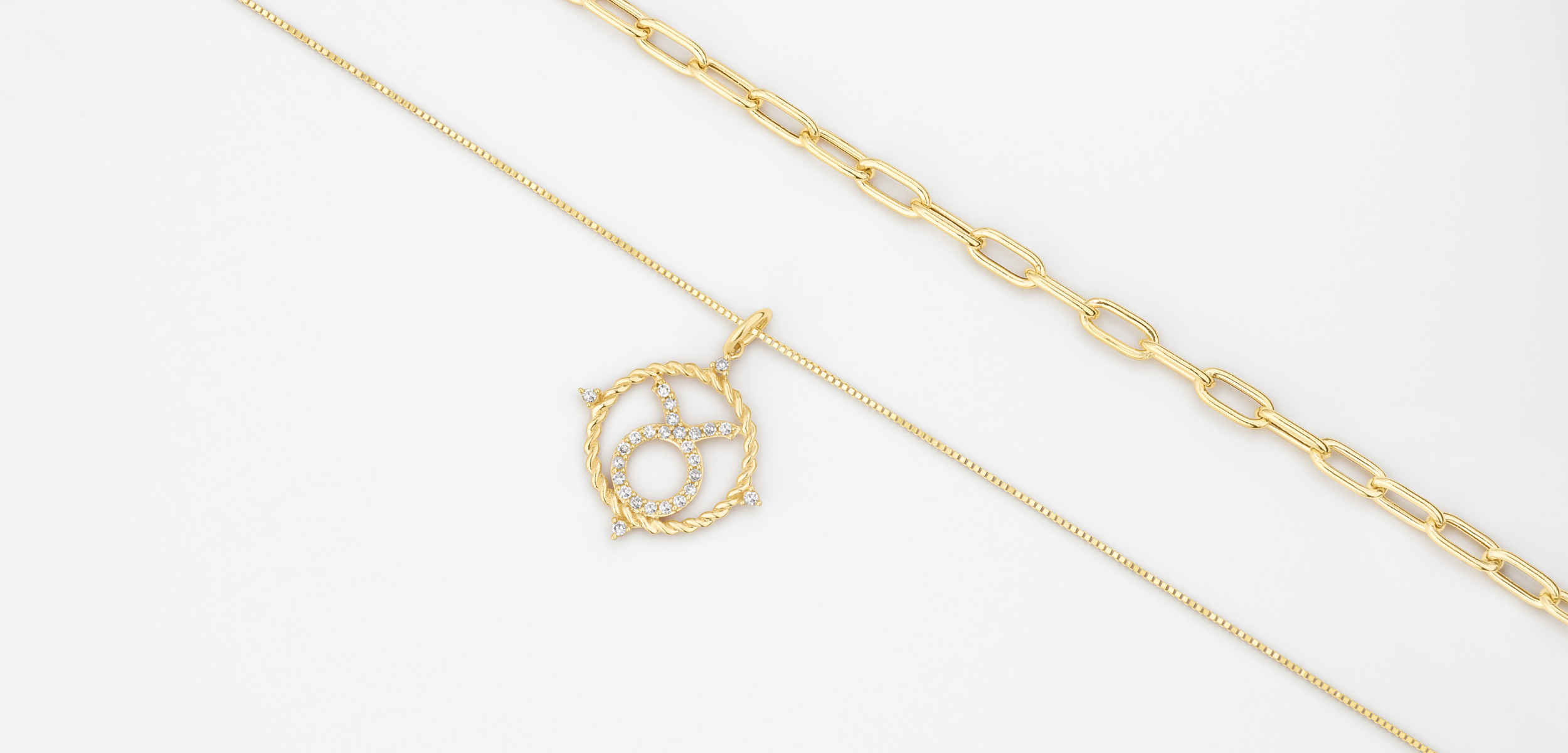 Flatlay of yellow gold chains, one with a zodiac pendant.
