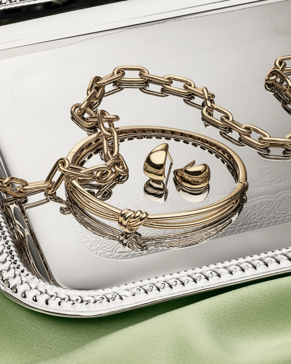 Flay lay of bold gold jewellery on silver tray
