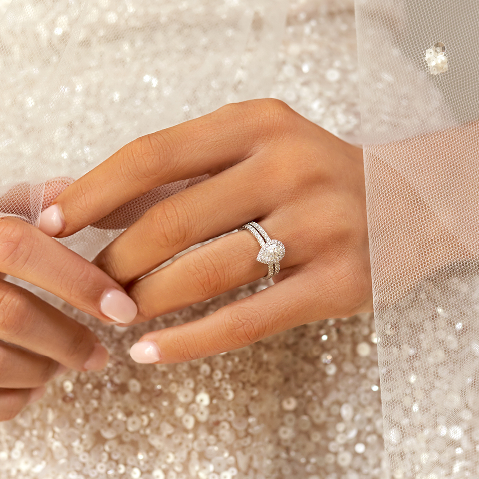 Bride holding hand wearing diamond engagement ring in sequent dress