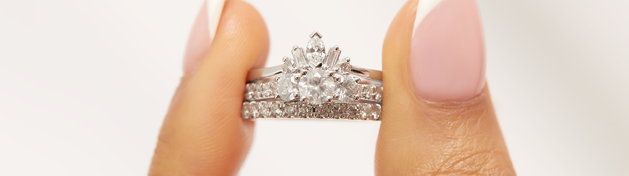 Holding a bridal set featuring a three stone engagement ring