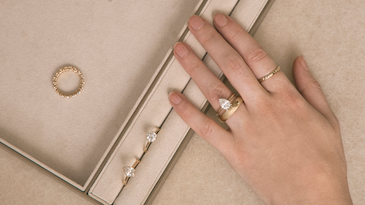 Close up of different engagement rings alongside a model's hand wearing an engagement ring and wedding band 