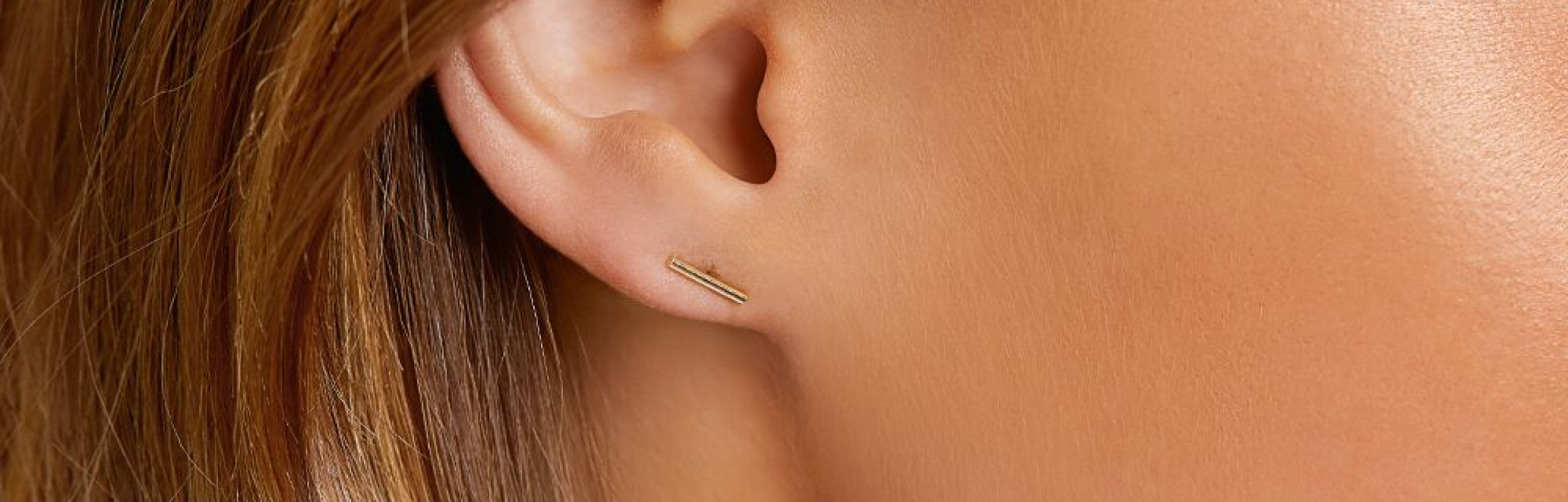 gold bar earring in earlobe