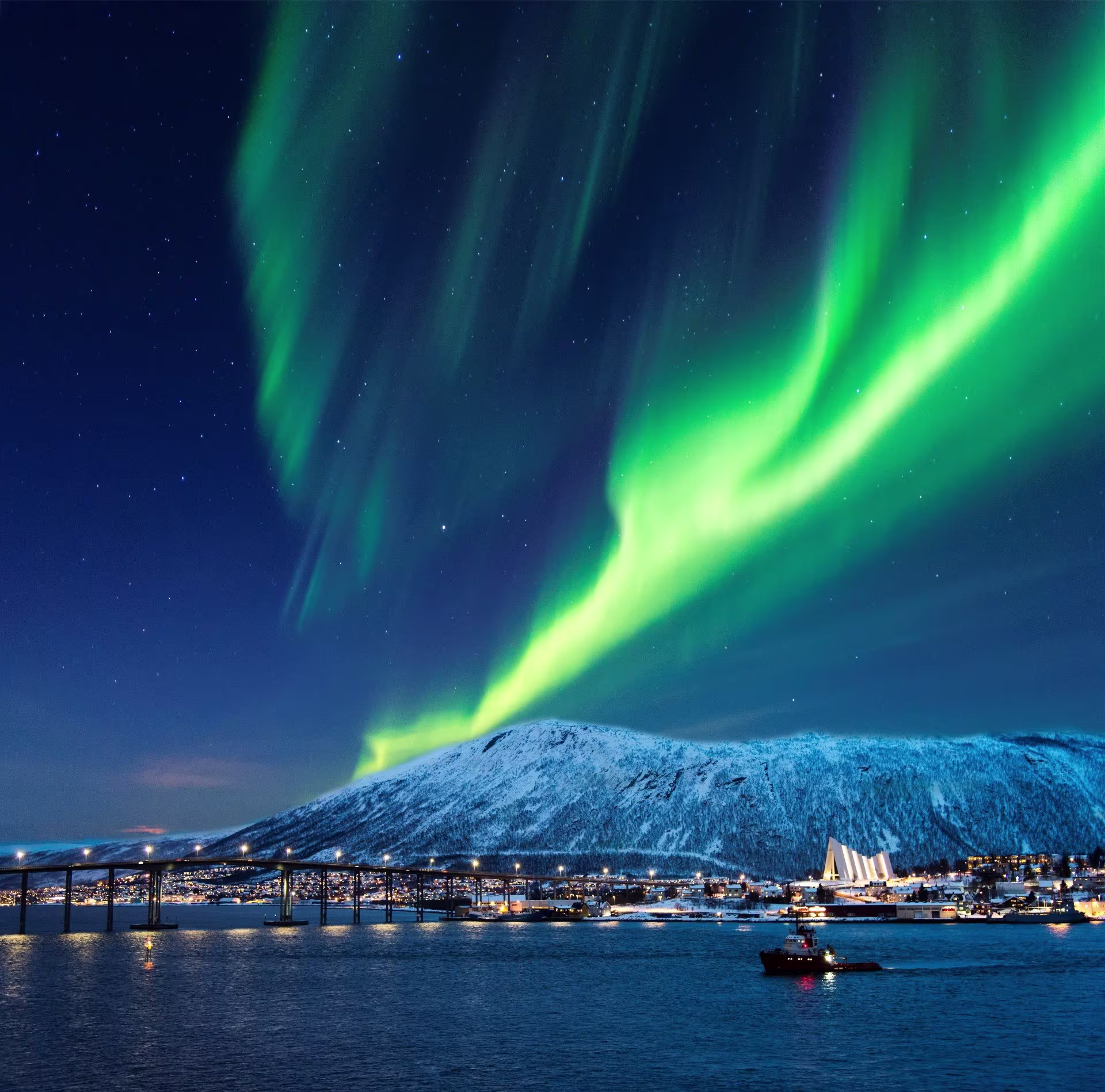 Aurora Borealis over Tromsø fjord and Arctic Cathedral in snowy northern Norway
