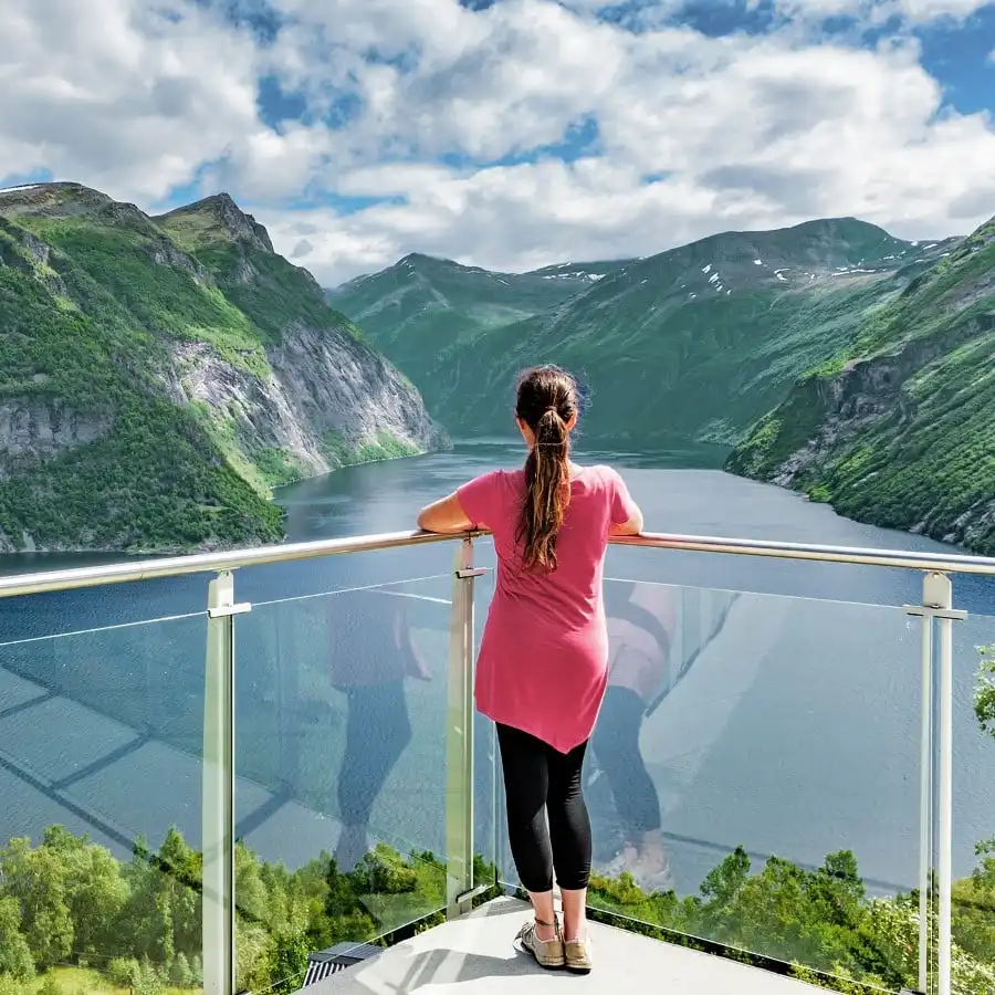 Woman standing on a balcony enjoying the view over the Sunnmøre Alps