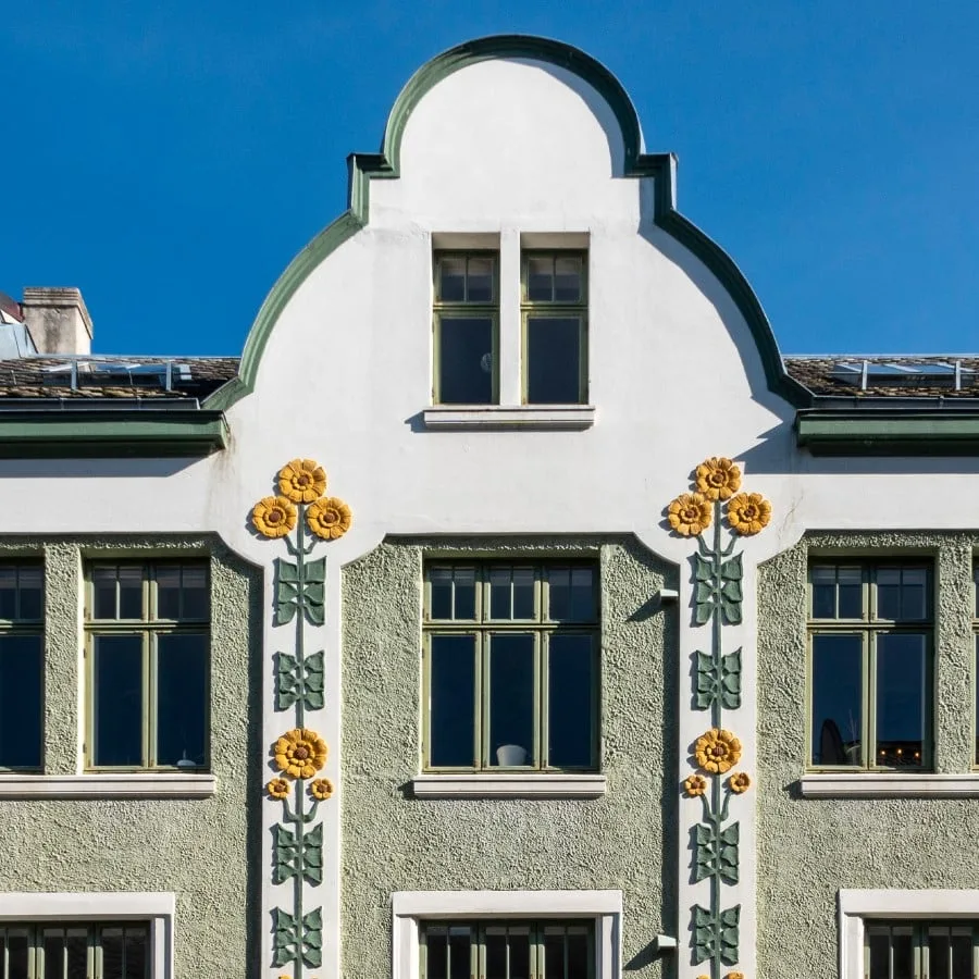 Green building with pink flowers on it, building on the Art Nouveau walk in Aalesund