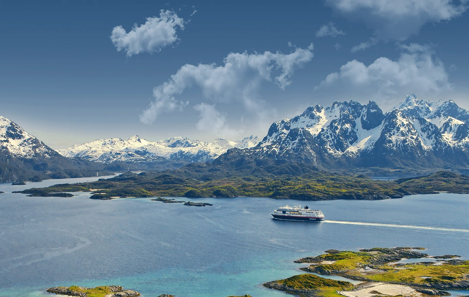 Hurtigruten Norway ship sailing in Raftsundet, Northern Norway. The water is turquoise and the peaks are covered in snow