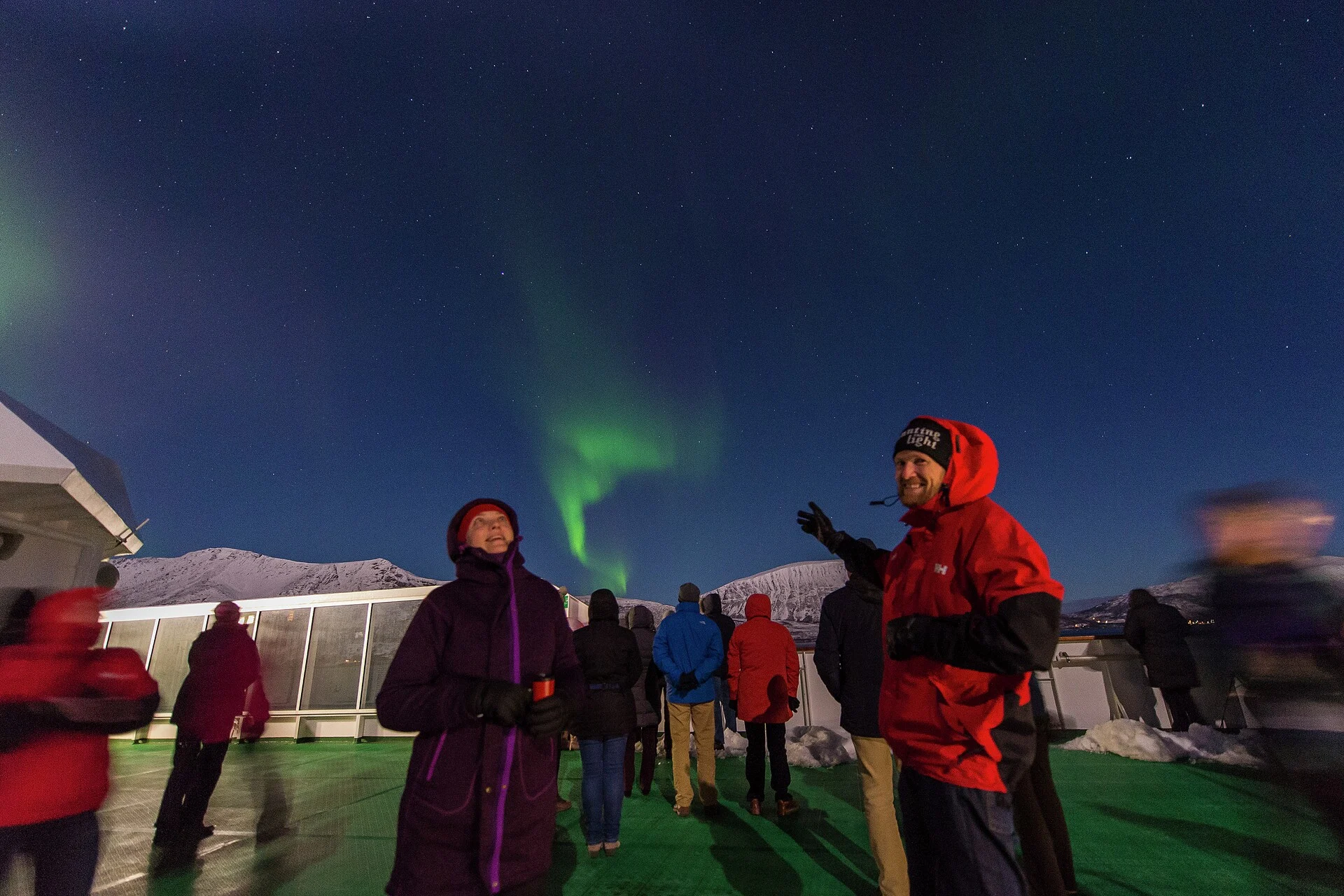 A group of passengers looking at the Northern Lights from the deck of a Hurtigruten ship