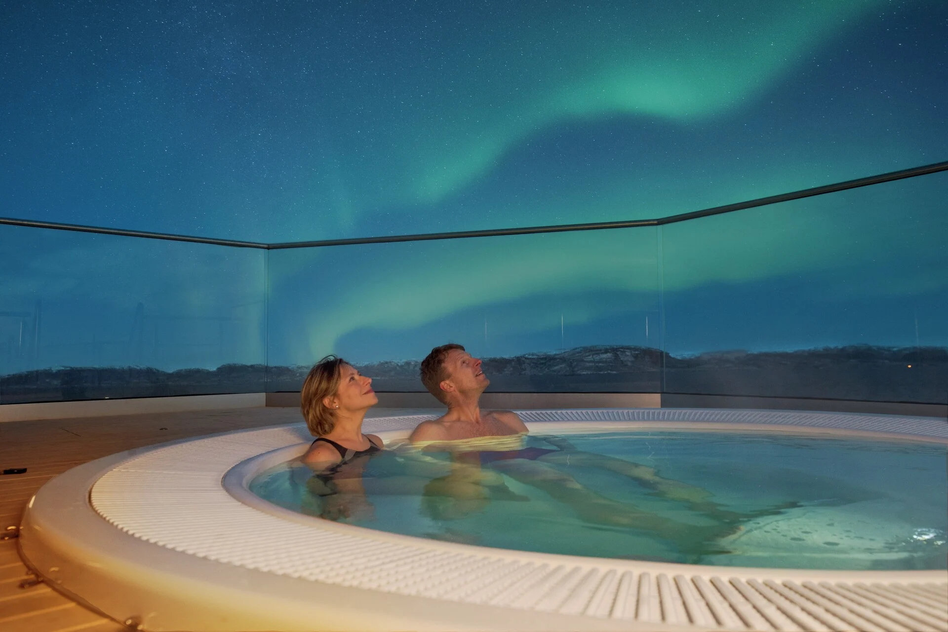 Northern Lights above a hot tub on deck on a Hurtigruten cruise in Norway