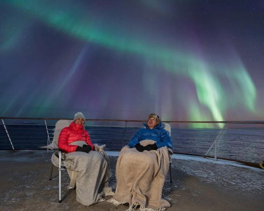 A couple watching the Northern Lights on deck of a Hurtigruten ship in Norway