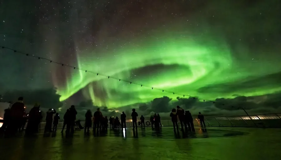 Gäste beobachten ein bemerkenswertes Nordlicht vom Deck eines Schiffs von Hurtigruten aus