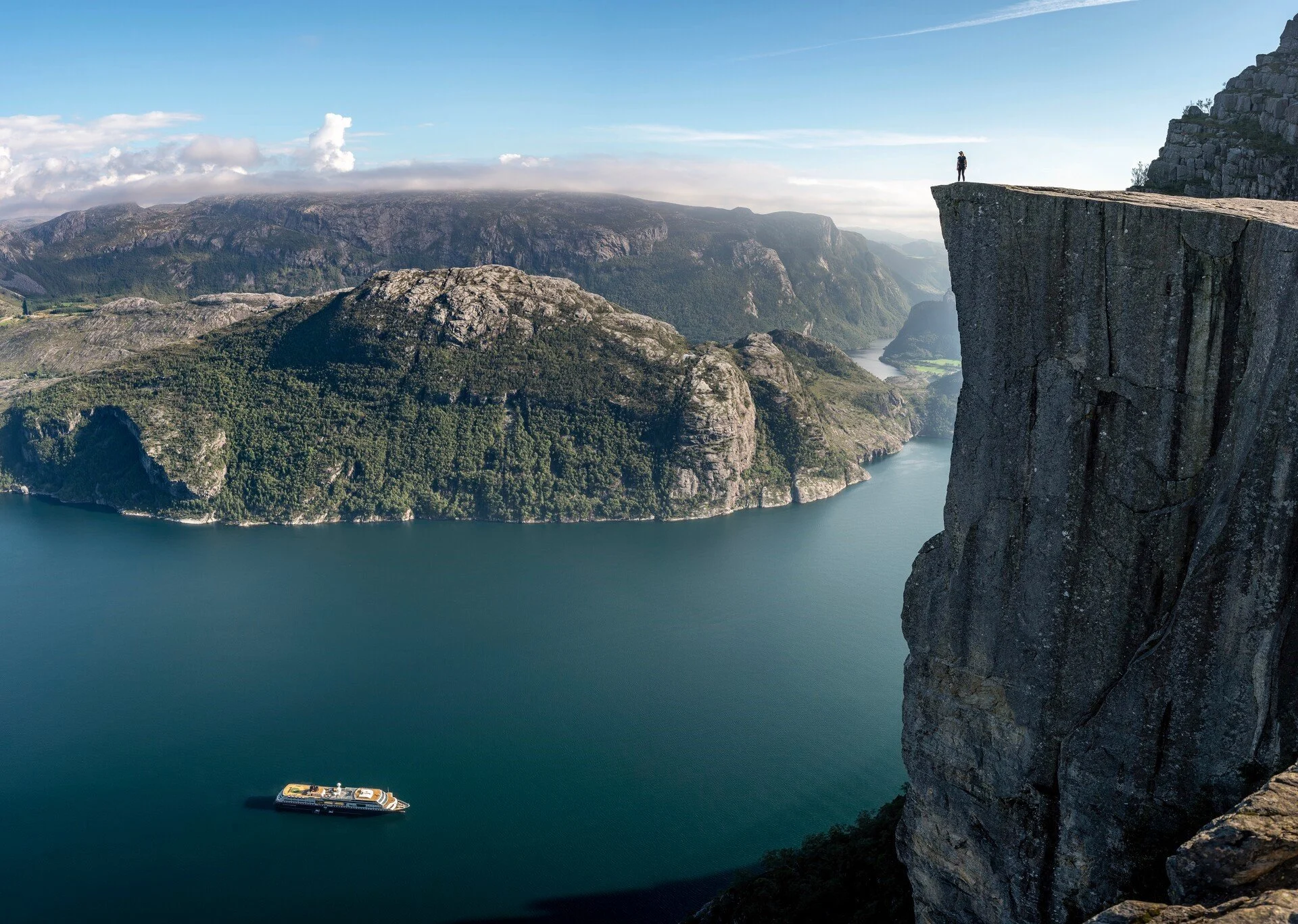 A hiker standing on Pulpit Rock looking down on a Hurtigruten ship in Lysefjord