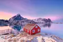A red rorbuer (fisherman's hut) against the snow-covered mountains in Reine in the Lofoten Islands