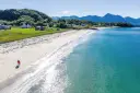 A couple walk along a beautiful white-sand beach on the island of Senja in Norway