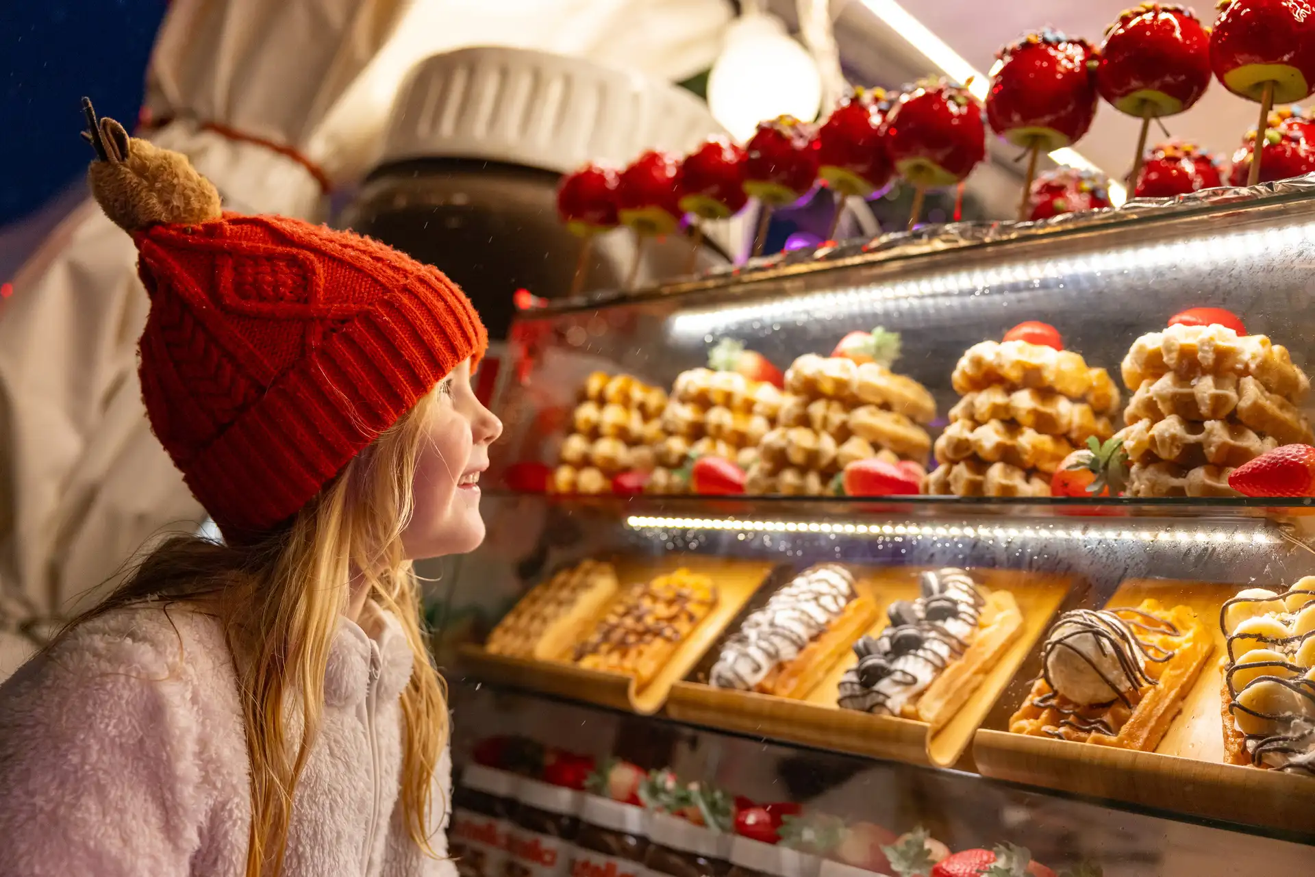 A girl looking at toffee apples on sale at a Christmas market in Bergen, Norway