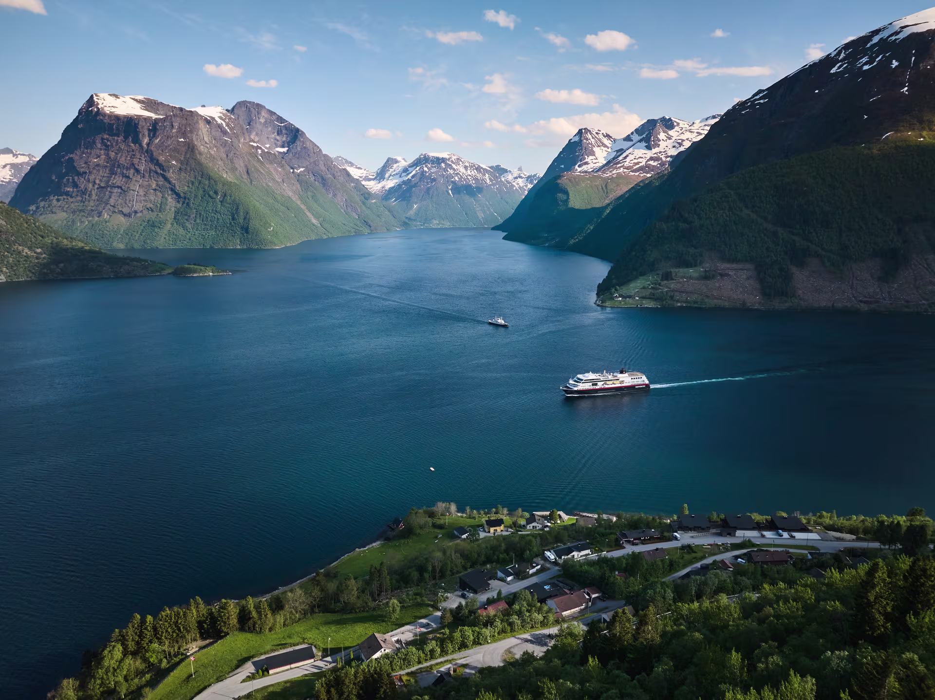 MS Trollfjord sailing through Hjorundfjorden with snow capped mountains in the background