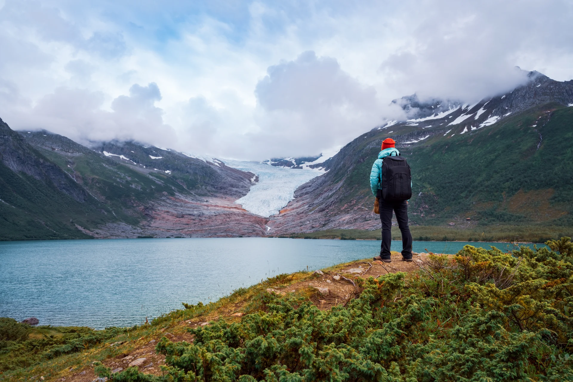 A hiker looking out at Svartisen Glacier