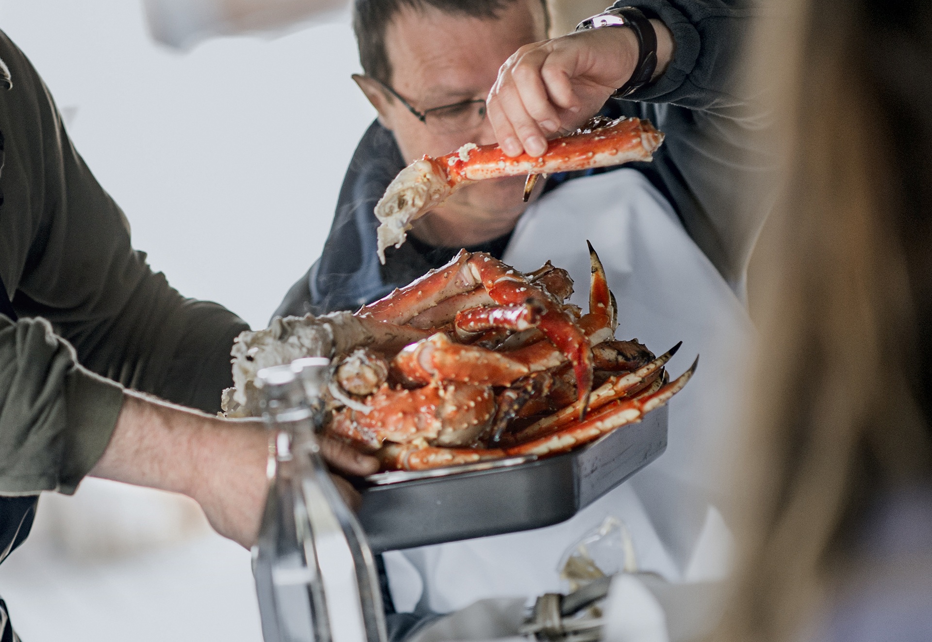 man-holding-large-king-crab-leg-being-served-kirkenes-norway-HGR-51295-orjan-bertelsen
