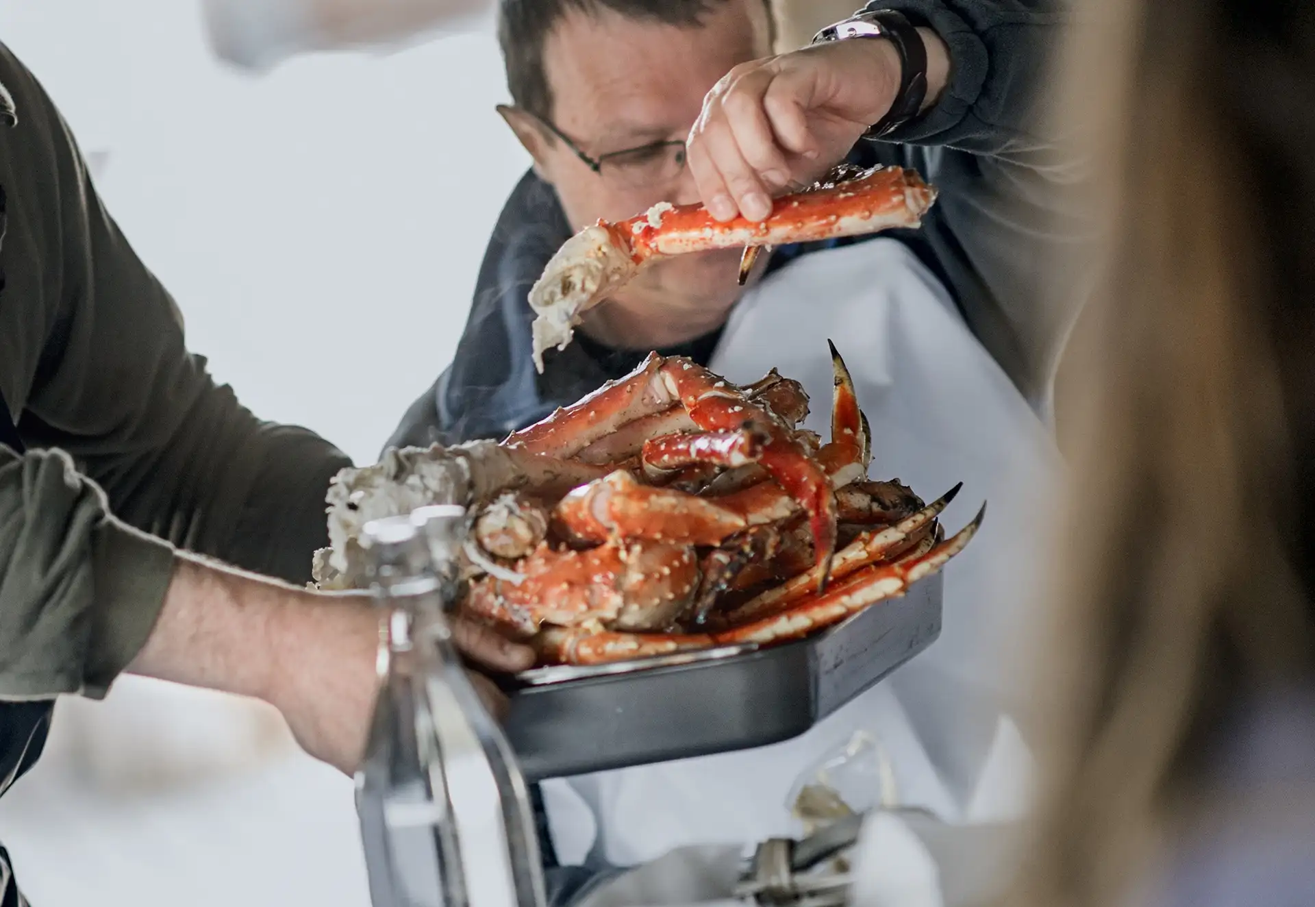 man-holding-large-king-crab-leg-being-served-kirkenes-norway-HGR-51295-orjan-bertelsen