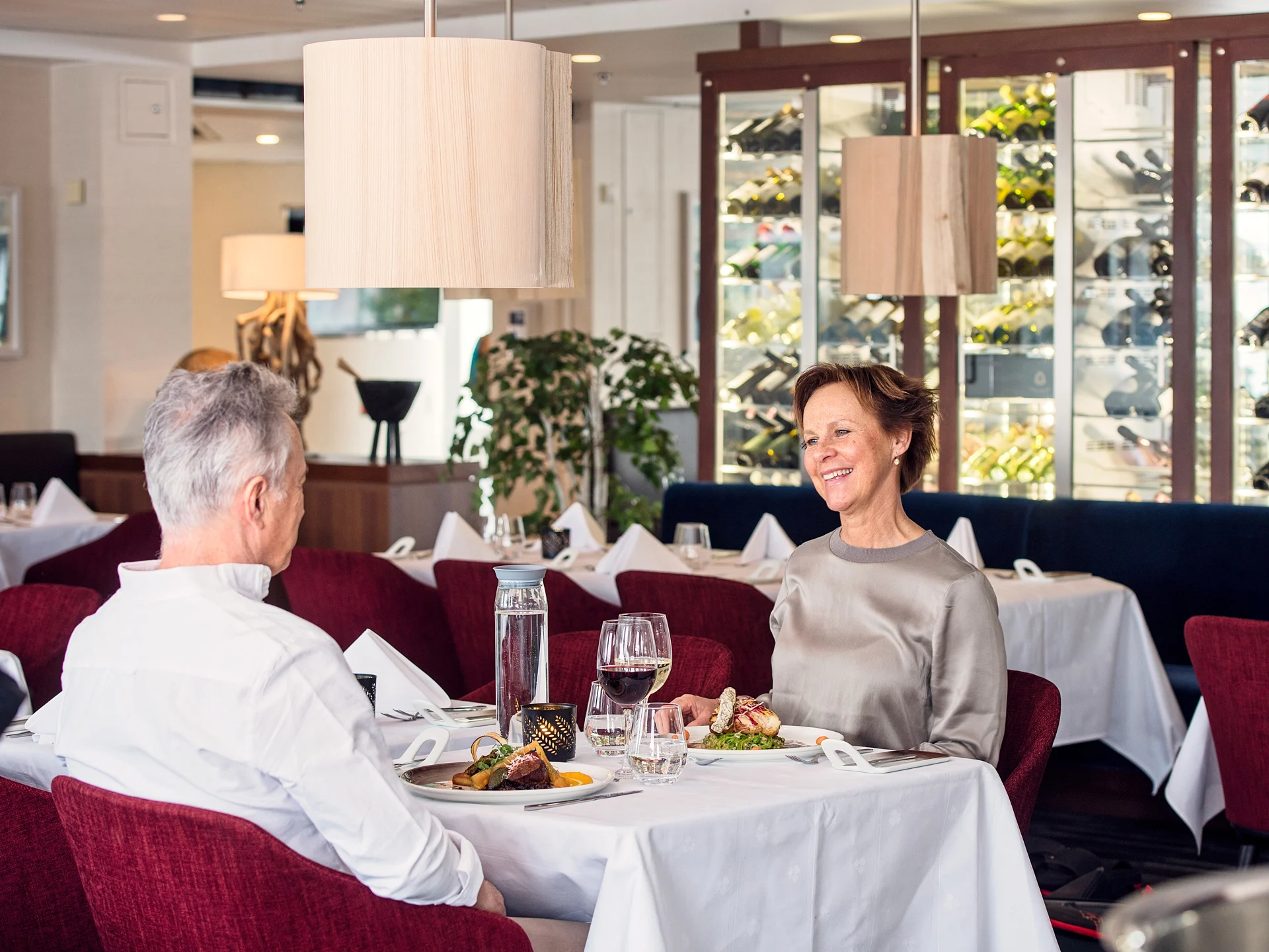 Gäste sitzen im Restaurant auf einem Hurtigruten Schiff