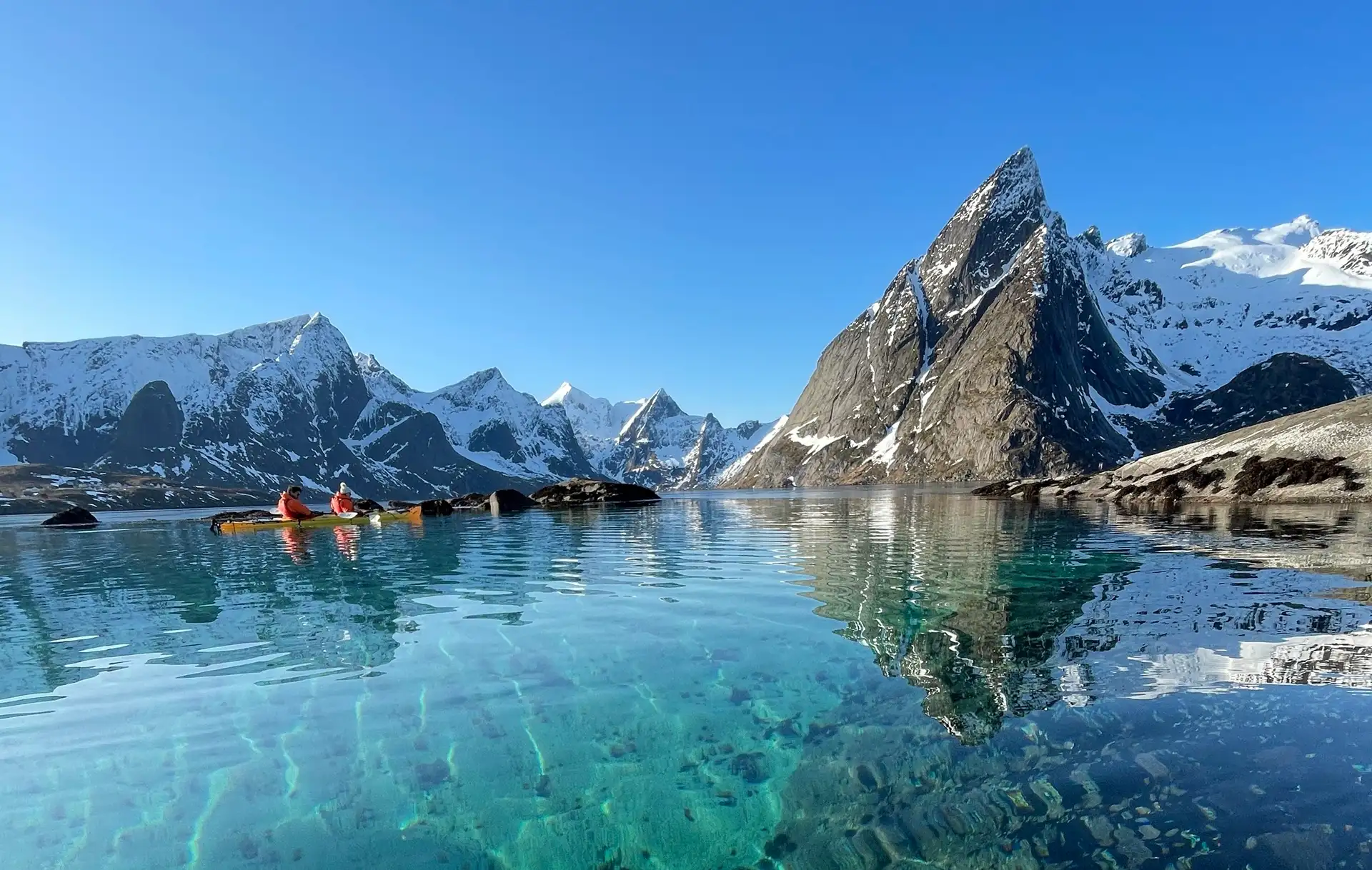 people-kayak-fjords-clear-turquoise-water-snow
