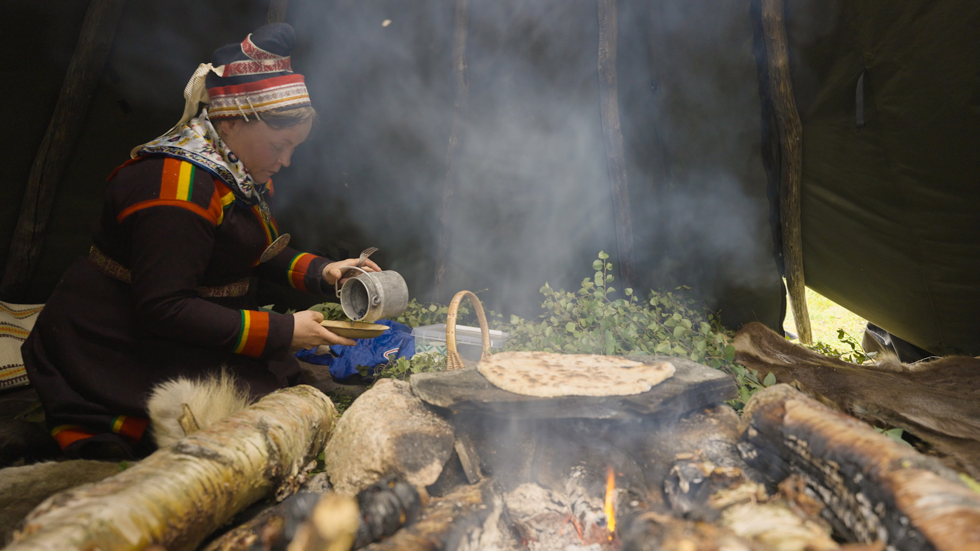 Hurtigruten Sámi Culinary Ambassador Máret Rávdná Buljo cooking on a fire in Norway