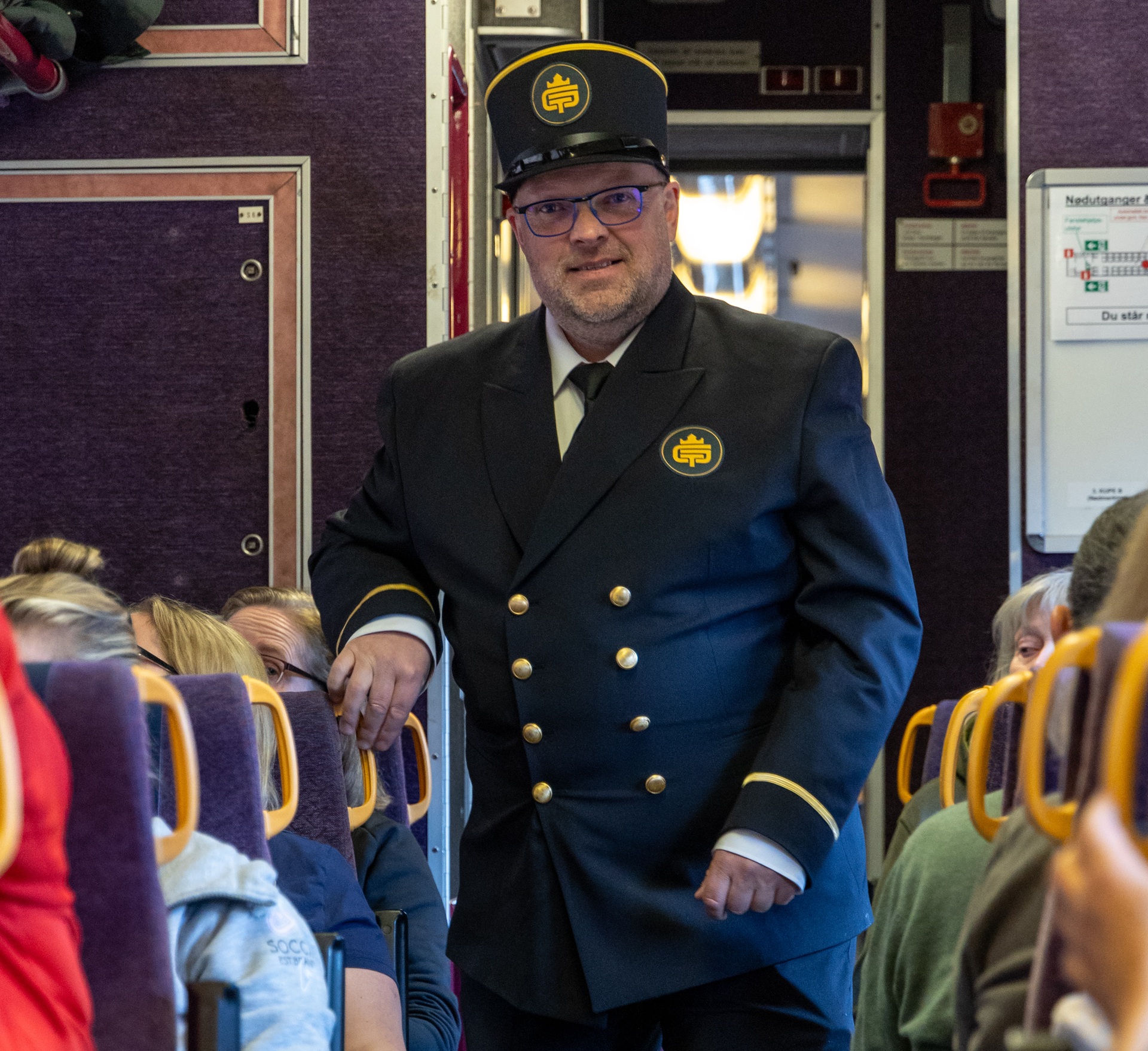 golden-train-attendant-walking-through-aisle-andalsnes-23-apr-2024