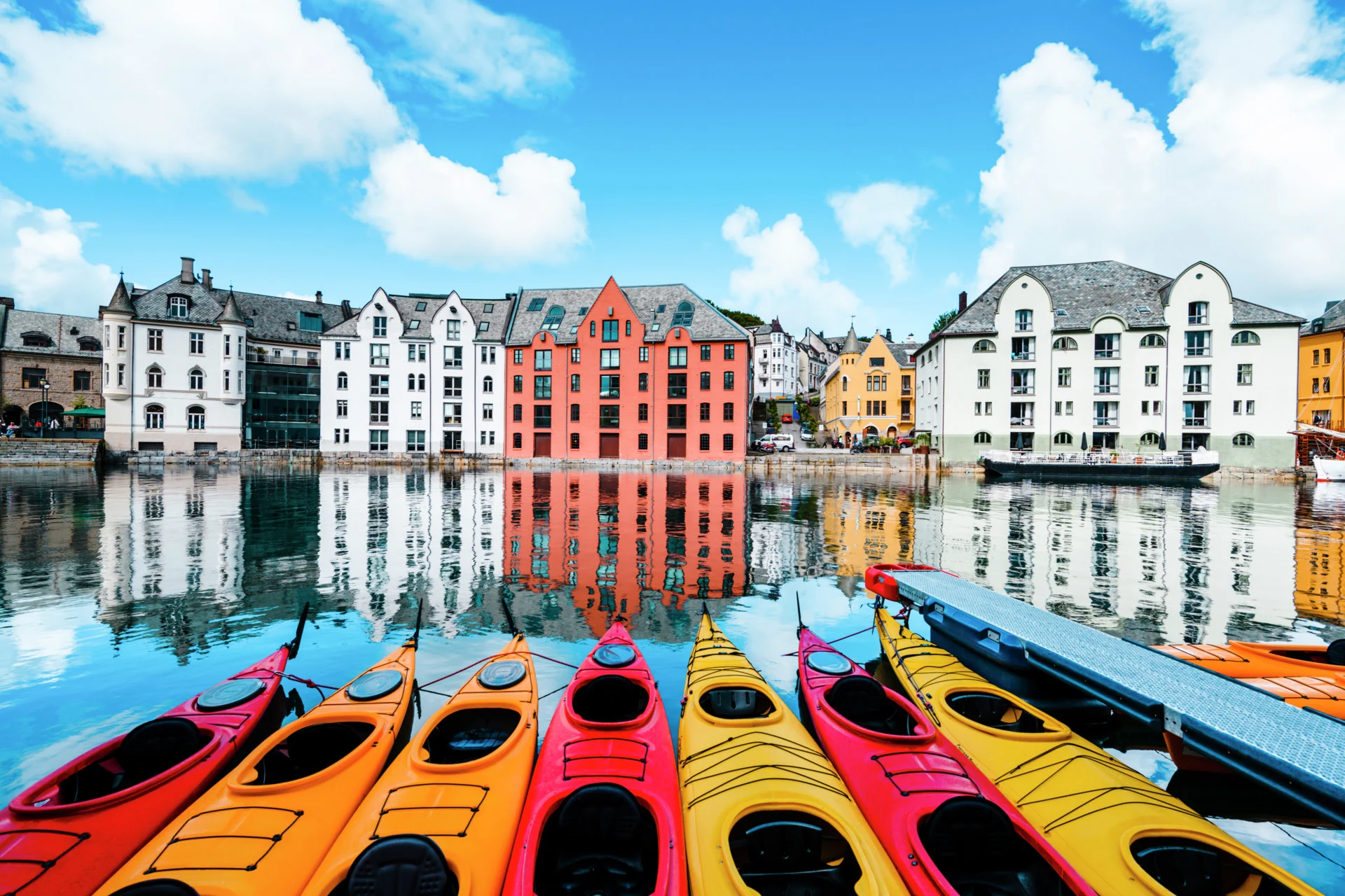 Kayaks on the canal in front of a row of coloured houses in Ålesund