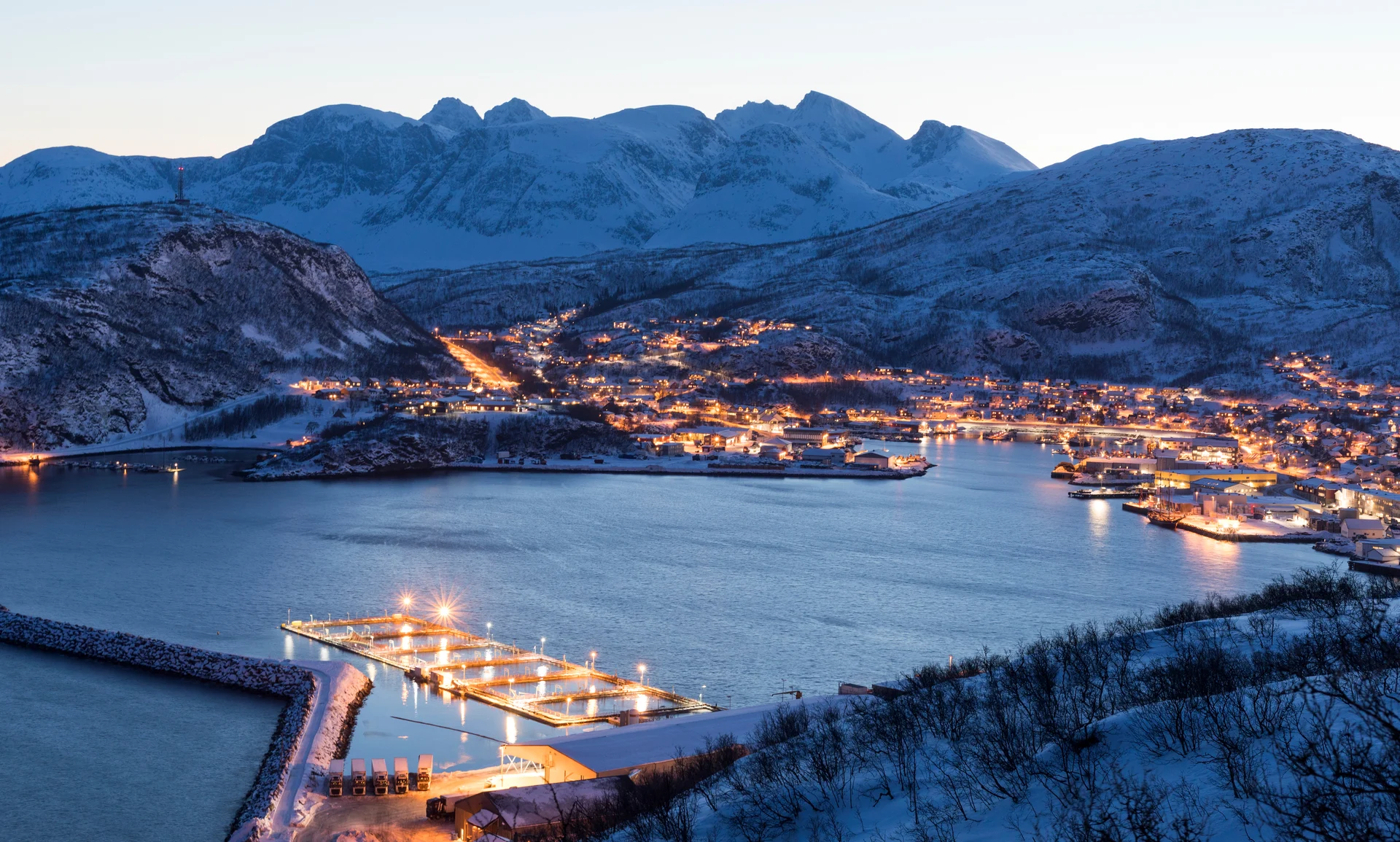 Vue sur Skjervøy, en Norvège, le soir, entourée de montagnes enneigées.