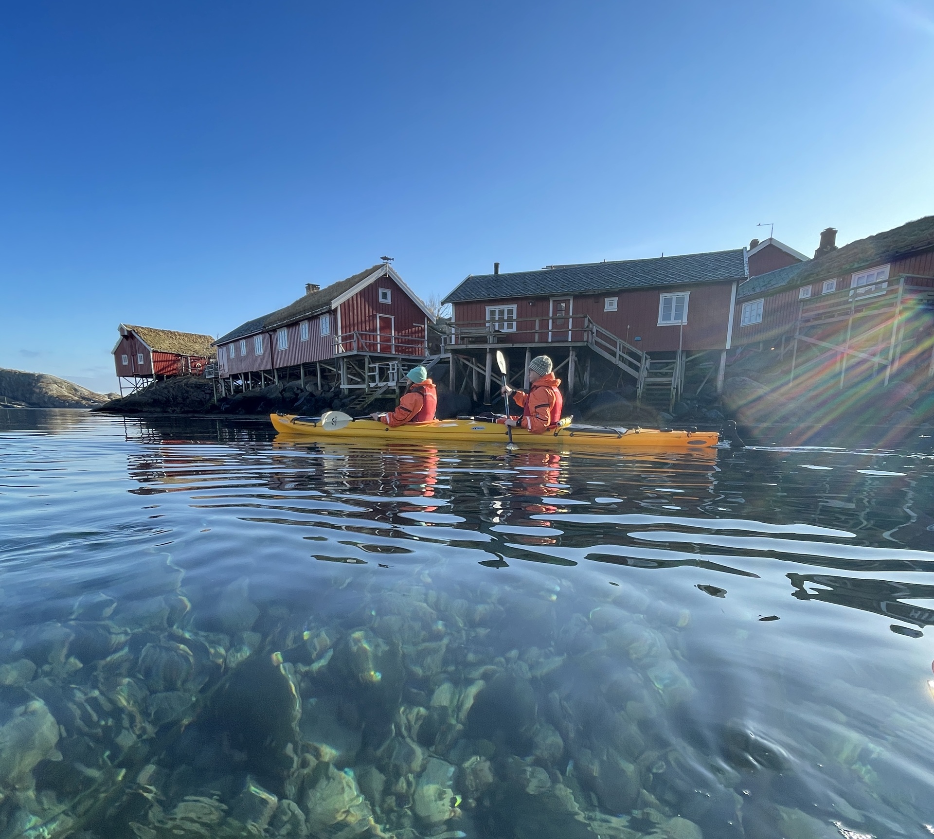 people-yellow-kayak-clear-water-blue-sky-red-houses